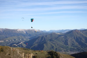 Pilote de parapente en vol thermique au-dessus des reliefs de Digne-les-Bains